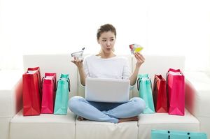 買い物袋を並べてカードを見る女性