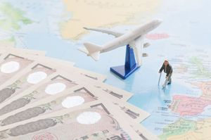 世界地図の上にお札と飛行機と杖をついた人の模型