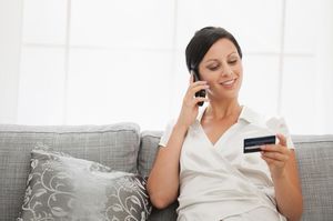 ソファーで電話しながらカードを持つ女性