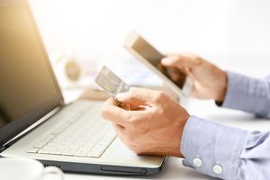 クレジットカードを見ながらスマホをPCを触る会社員