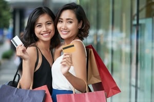 買い物バックとカードを持ち微笑む女性2人