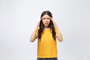 頭を抱える黄色い服を着た女性