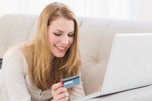 パソコンとクレジットカードを見ながら微笑む女性