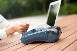 ノートパソコンとカードリーダを操作する手元