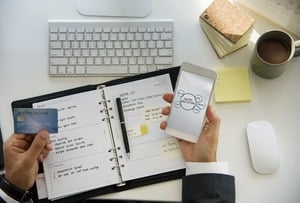 スケジュール長の上でスマホとカードを持つ手元