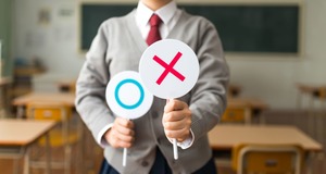 ○と×のカードを持つスーツ姿の男性