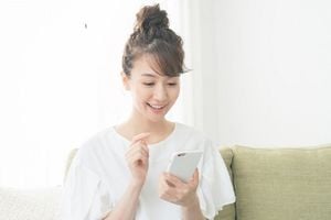 スマホを見て微笑む白い服を着た女性