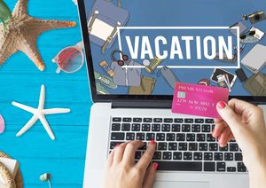 「Vacation」と表示されたパソコン画面の前でカードを持つ手