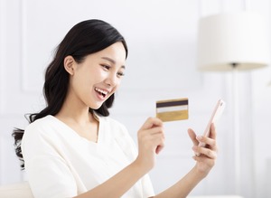 クレジットカードとスマホを見る女性