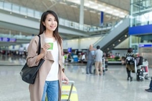 空港でクレジットカードとスーツケースを持ち微笑む女性