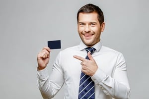 ブラックカードを指さし微笑むビジネスマン