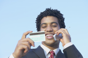 クレジットカードを見ながら携帯電話で話す男性