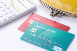 緑と赤のクレジットカードと黄色いがま口と電卓