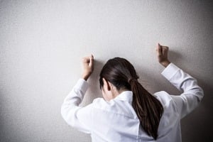 クレヒスが育たず壁に両手打ちひしがれる女性