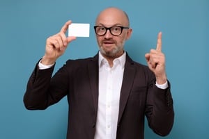 クレジットカードを持ち指をさすメガネの男性