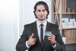 クレジットカードを持ち親指を立てる男性