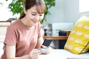 クレジットカードを持ち見つめる女性
