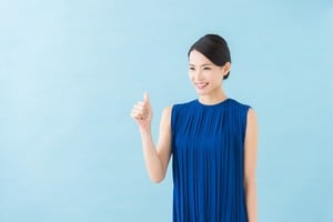 青い服を着て親指を立てる笑顔の女性