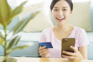 クレジットカードとスマホを持つ笑顔の女性